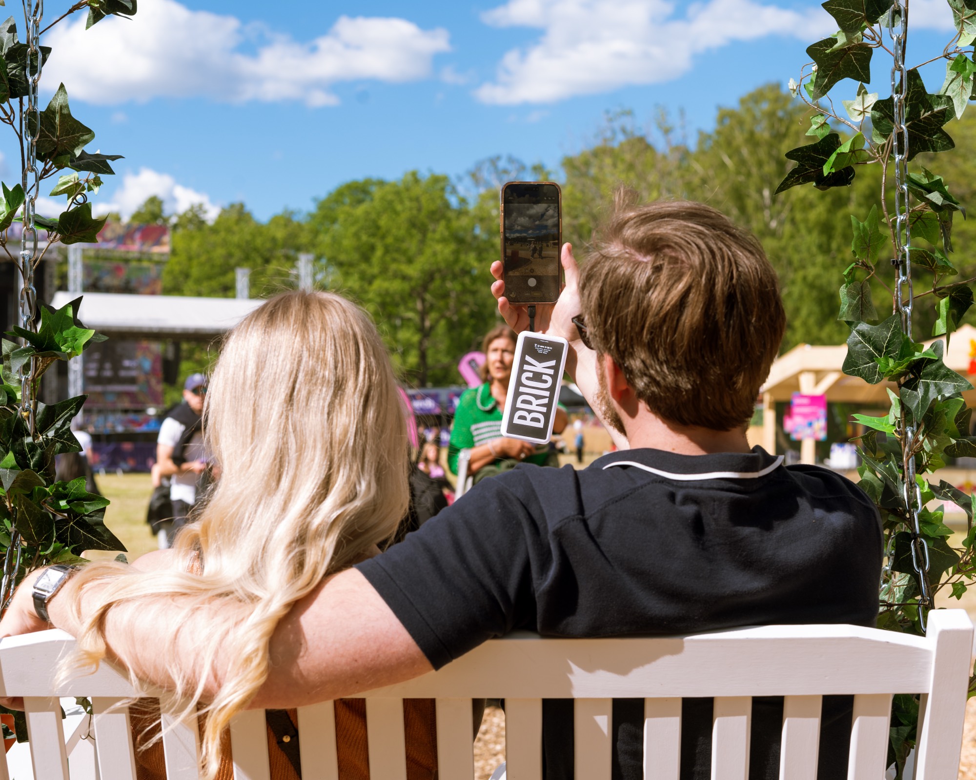 Two guests filming a festival stage with a Brick powerbank on the phone