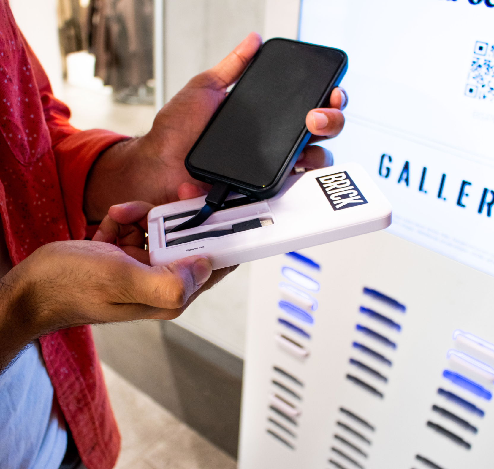 Hand holding phone and Brick power bank next to a Large station