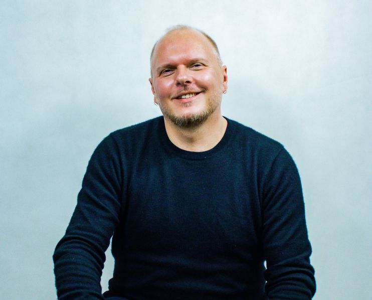 A smiling man with short hair and a dark blue sweatshirt