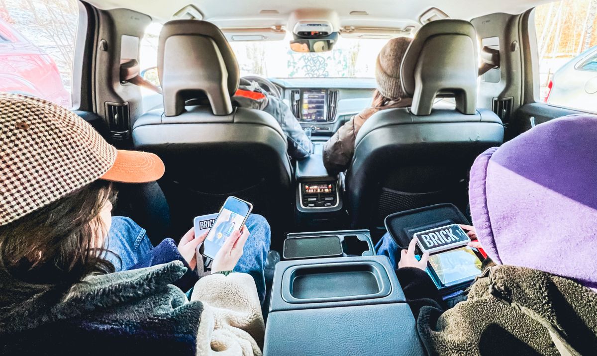 Young people sitting in the back of a car charging a phone and an Nintendo switch with a Brick powerbank