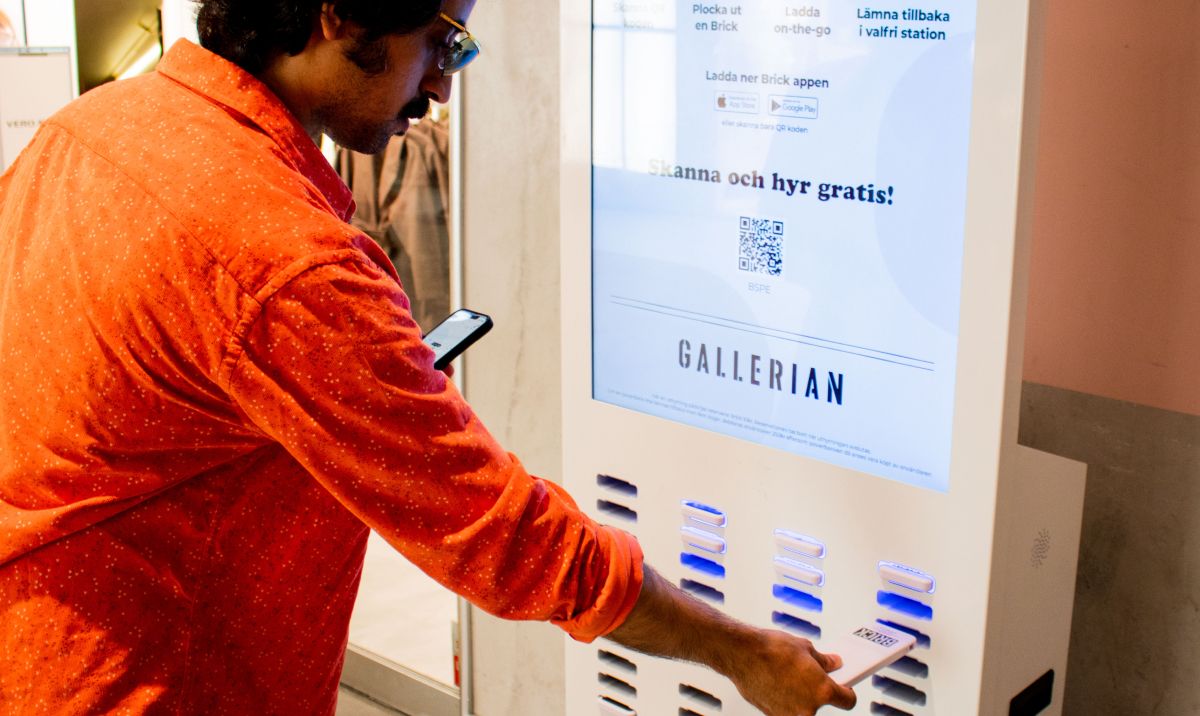 Man taking out a charger from a Brick 48 slot powerbank sharing station