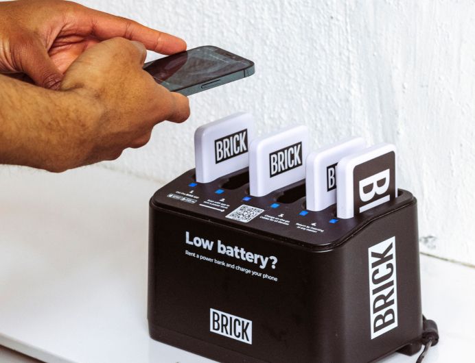 Person scnning a QR code on a Brick 6 slot powerbank station with his phone